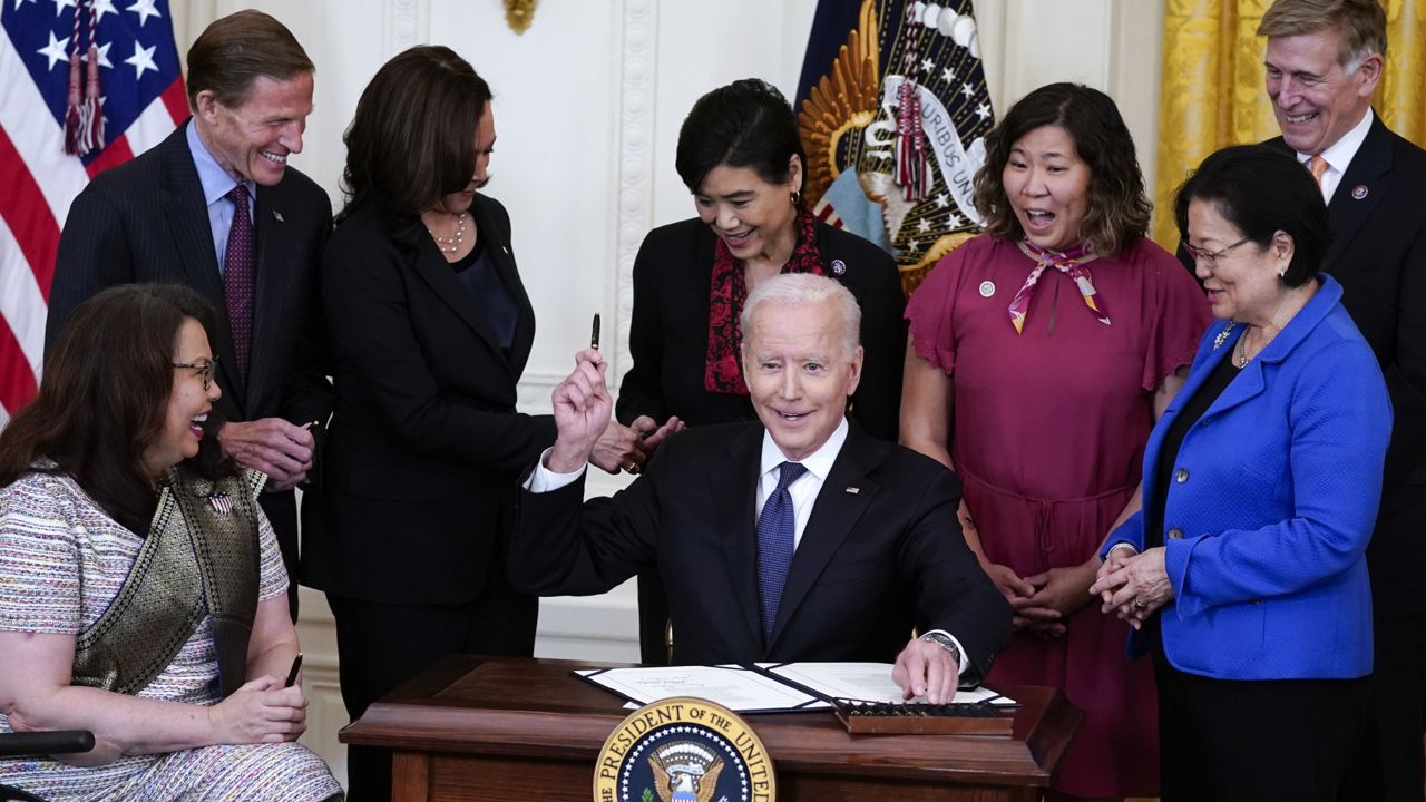 President Joe Biden hands out a pen after signing the COVID-19 Hate Crimes Act, in the East Room of the White House, Thursday, May 20, 2021, in Washington. (AP Photo/Evan Vucci)