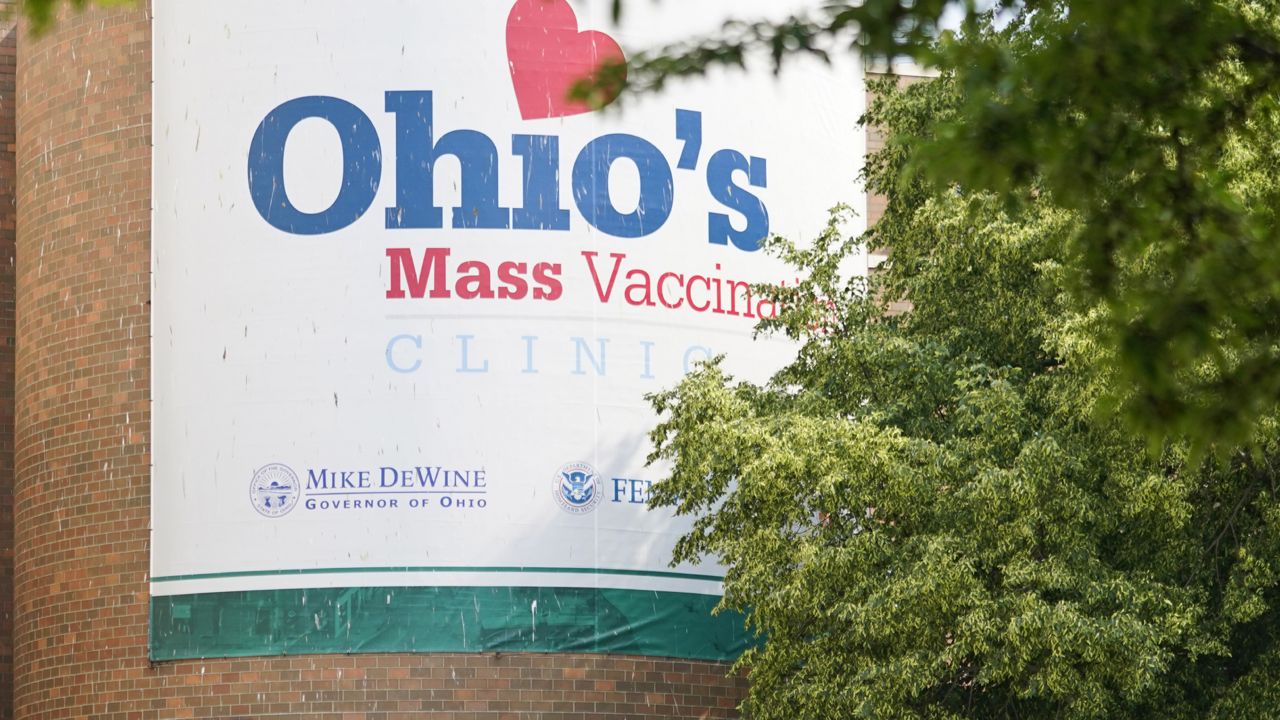 People walk past sign displayed for Ohio's COVID-19 mass vaccination clinic at Cleveland State University, Tuesday, May 25, 2021, in Cleveland. (AP Photo/Tony Dejak)