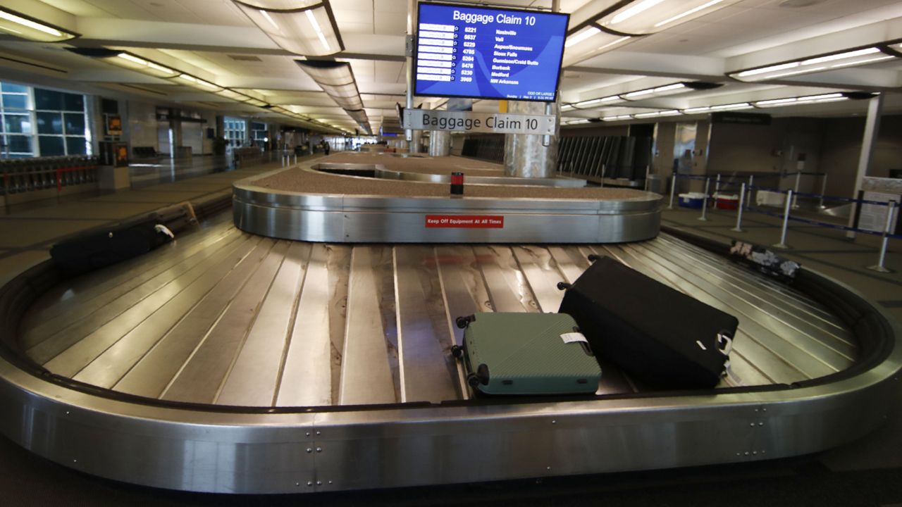 FILE: Two pieces of luggage are carried on a carousel in an otherwise empty baggage claim area at Denver International Airport. (AP Photo/David Zalubowski)
