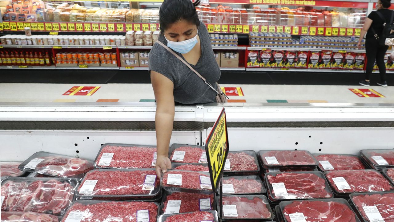 FILE - A shopper wears a mask as she looks over meat products at a grocery store in Dallas. (AP Photo/LM Otero, File)