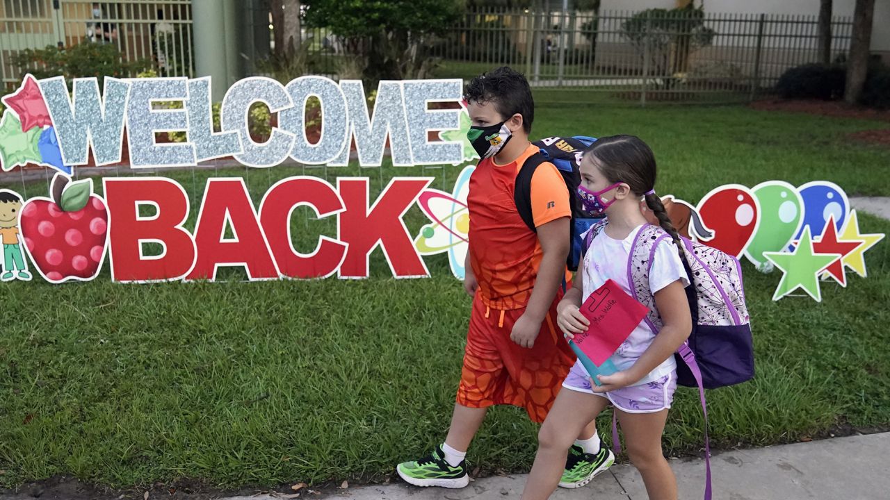 FILE - In this Tuesday, Aug. 10, 2021 file photo, Students wearing protective masks walk past a "Welcome Back" sign before the first day of school at Sessums Elementary School in Riverview, Fla. (AP Photo/Chris O'Meara, File)