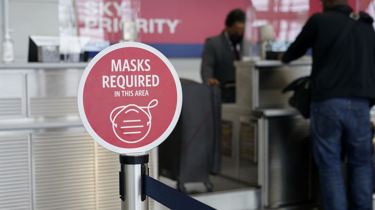 FILE: A sign advising that masks are required to protect against the spread of COVID-19 stands at a Delta Air Lines check-in counter at Ronald Reagan Washington National Airport Tuesday, May 25, 2021, in Arlington, Va. (AP Photo/Patrick Semansky)