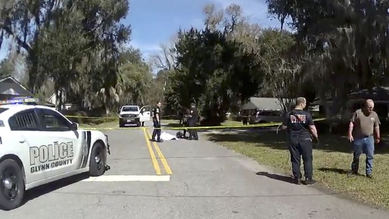 FILE: In this Feb. 23, 2020 image taken from Glynn, Ga., County Police body camera video, authorities, rear, stand over the covered body of Ahmaud Arbery. (Glynn County Police via AP)