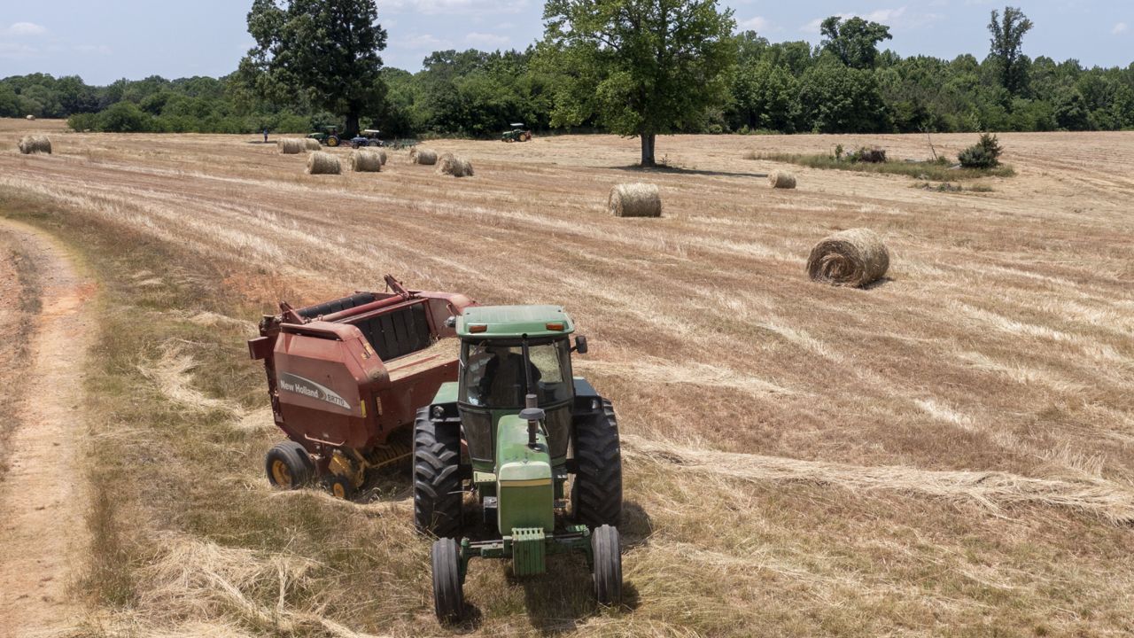 FILE: Farmer John Boyd Jr., runs his hay bailer at his farm in Boydton, Va., Thursday, May 27, 2021. (AP Photo/Steve Helber)