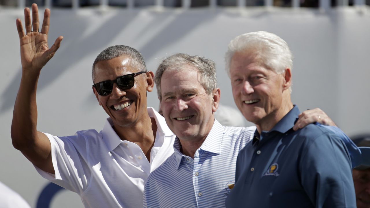 Former U.S. Presidents, from left, Barack Obama, George Bush and Bill Clinton greet spectators on the first tee before the first round of the Presidents Cup at Liberty National Golf Club in Jersey City, N.J., Thursday, Sept. 28, 2017. (AP Photo/Julio Cortez)