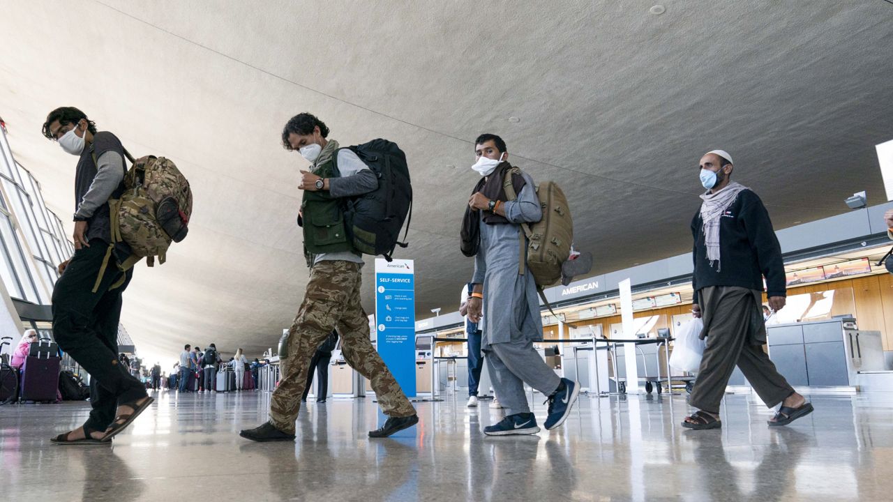 FILE: People evacuated from Kabul, Afghanistan, walk through the terminal before boarding a bus after they arrived at Washington Dulles International Airport, in Chantilly, Va., on Friday, Sept. 3, 2021. (AP Photo/Jose Luis Magana)