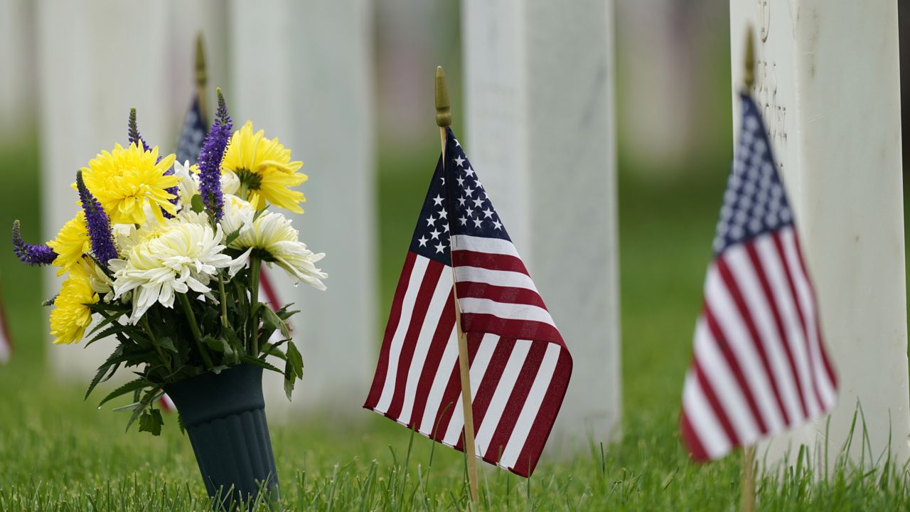 FILE: Flags and tributes mark the Memorial Day holiday are placed among the headstones in Fort Logan National Cemetery Monday, May 31, 2021. (AP Photo/David Zalubowski)