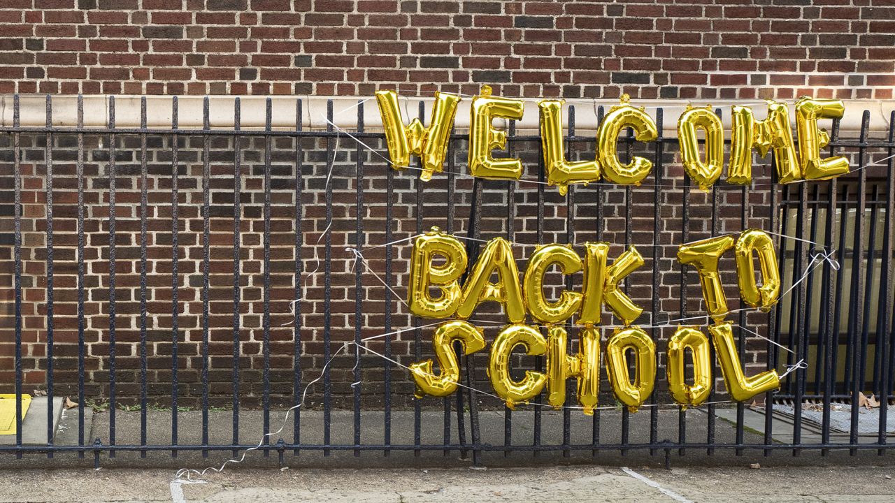 FILE - In this Sept. 13, 2021, file photo, a girl passes a "Welcome Back to School" sign as she arrives for the first day of class at Brooklyn's PS 245 elementary school. (AP Photo/Mark Lennihan, File)