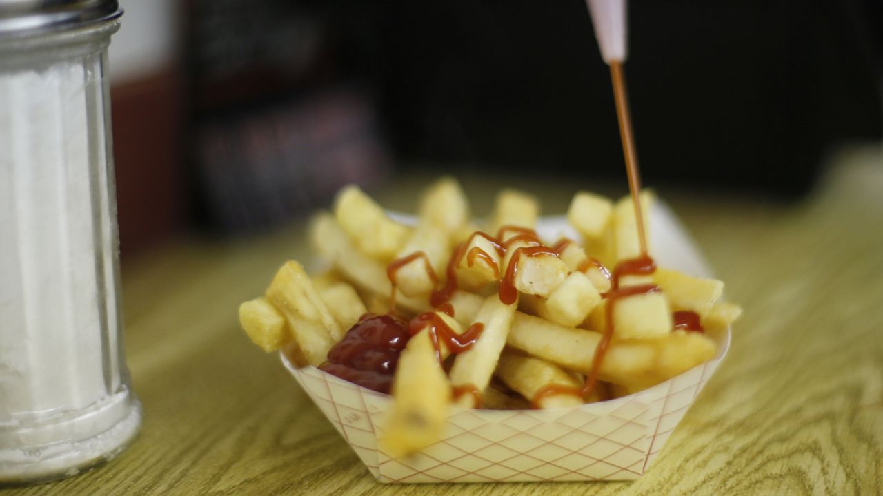 FILE - In this Thursday, June 26, 2014 file photo, a customer douses her french fries with ketchup at the Saco Drive-In in Saco, Maine. (AP Photo/Robert F. Bukaty, File )