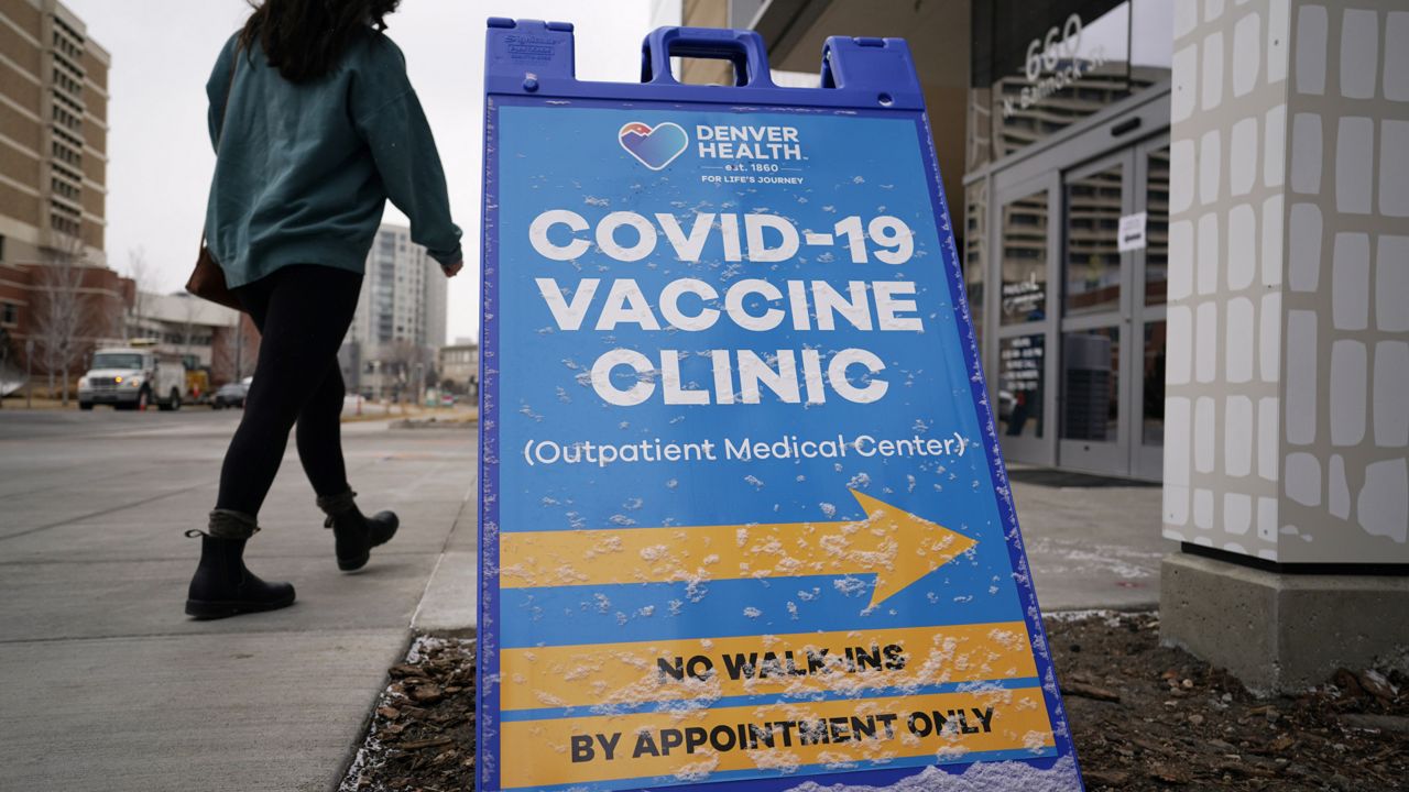 FILE - In this Feb. 13, 2021 file photo a woman heads in for a COVID-19 vaccination. (AP Photo/David Zalubowski,File)