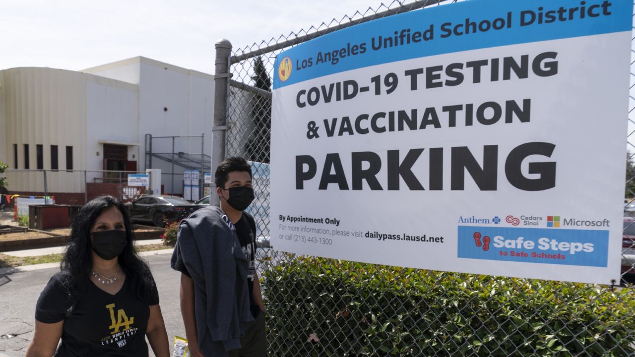 FILE - In this April 15, 2021, file photo, people walk home after getting tested at a Los Angeles Unified School District COVID-19 testing and vaccination site in East Los Angeles. (AP Photo/Damian Dovarganes, File)