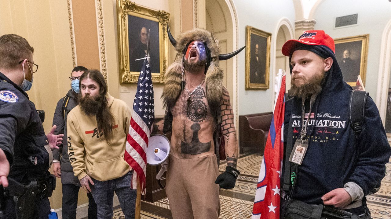 FILE - In this Wednesday, Jan. 6, 2021 file photo, supporters of President Donald Trump, including Jacob Chansley, center with fur and horned hat, are confronted by Capitol Police officers outside the Senate Chamber inside the Capitol in Washington. A video showed Chansley leading others in a prayer inside the Senate chamber. (AP Photo/Manuel Balce Ceneta)