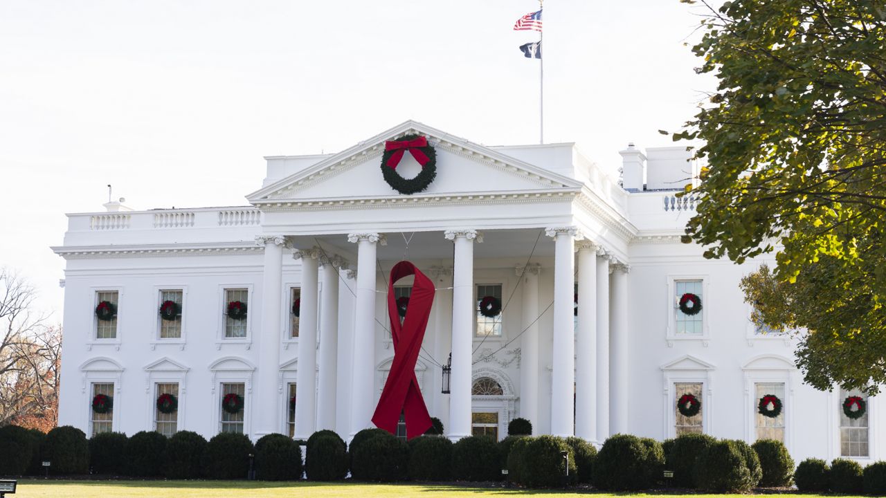 The North Portico of the White House is adorned with a huge red ribbon to commemorate the annual World AIDS Day, Wednesday, Dec. 1, 2021, in Washington. (AP Photo/Manuel Balce Ceneta)