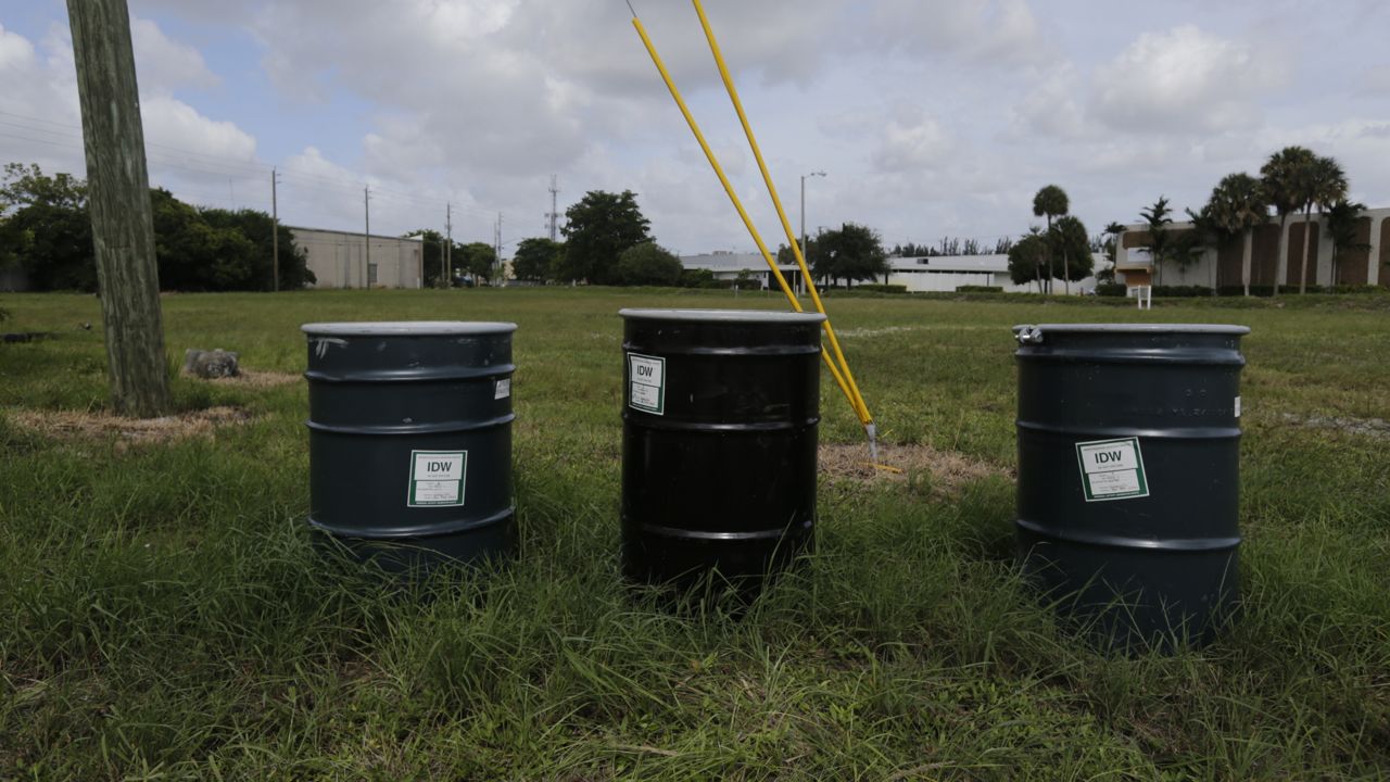 FILE - In this Sept. 6, 2017 file photo, barrels identified by stickers as IDW, or "investigation derived waste," full of soil and water, sit in a field designated by the EPA as an intensely polluted Superfund site called Anodyne North Miami Beach. (AP Photo/Jason Dearen, File)