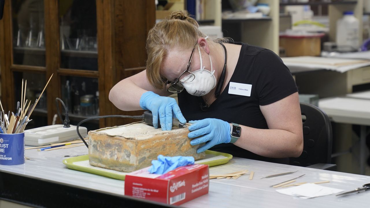 Conservator for the Virginia Department of Historic Resources, Chelsea Blake, works to open a time capsule that was removed form the pedestal that once held the statue of Confederate General Robert E. Lee on Monument Ave. Wednesday Dec. 22, 2021, in Richmond, Va. (AP Photo/Steve Helber)