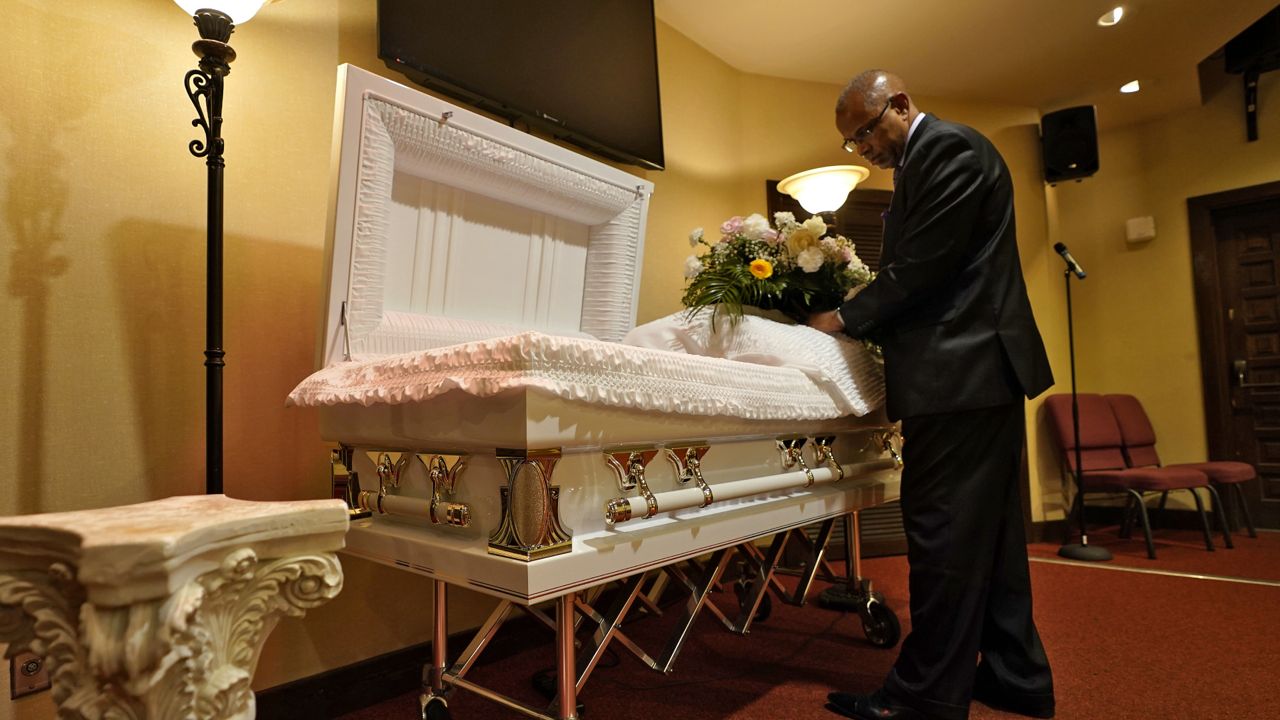 FILE: A funeral director at Wilson Funeral Home arranges flowers on a casket before a service Thursday, Sept. 2, 2021, in Tampa, Fla. (AP Photo/Chris O'Meara)