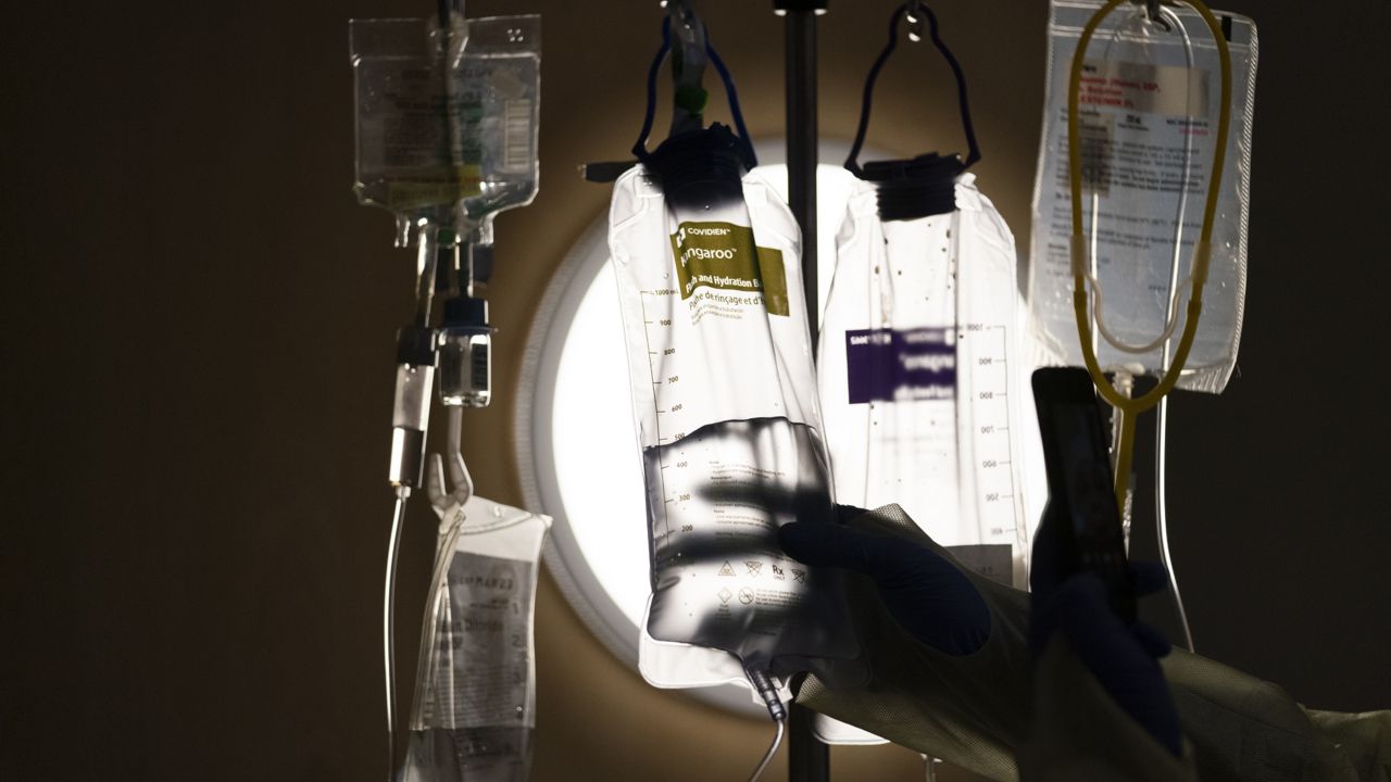 FILE: A nurse checks on IV fluids while talking to a COVID-19 patient at Providence Holy Cross Medical Center in Los Angeles, Monday, Dec. 13, 2021. (AP Photo/Jae C. Hong, File)