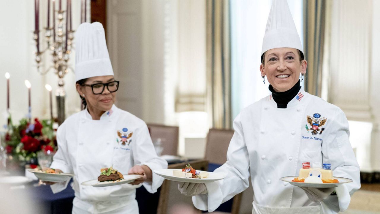 White House executive chef Cris Comerford, left, and White House executive pastry chef Susie Morrison, right, hold dishes during a media preview for the State Dinner with President Joe Biden and French President Emmanuel Macron in the State Dining Room of the White House in Washington, Wednesday, Nov. 30, 2022. The dinner will include a butter poached Maine lobster, beef with shallot marmalade, American artisanal cheeses, and an orange chiffon cake for desert. (AP Photo/Andrew Harnik)