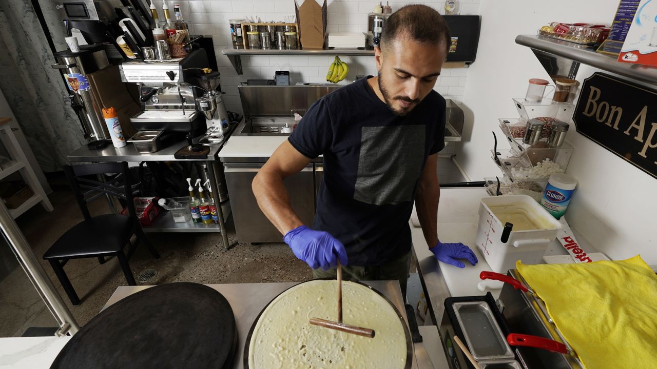 New U.S. citizen Jad "Jay" Jawad, owner of the Crepe House Cafe, who came to the U.S. as a refugee from war-torn Iraq, makes a crepe in his cafe on Friday, Sept. 4, 2020 in Phoenix. (AP Photo/Ross D. Franklin)