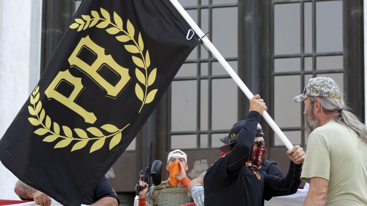 FILE - In this Sept. 7, 2020 photo, a protester carries a Proud Boys banner, symbol of a right-wing group, in Salem, Ore. Retailers including Amazon and eBay have pulled Proud Boys merchandise from their sites. (AP Photo/Andrew Selsky, File)