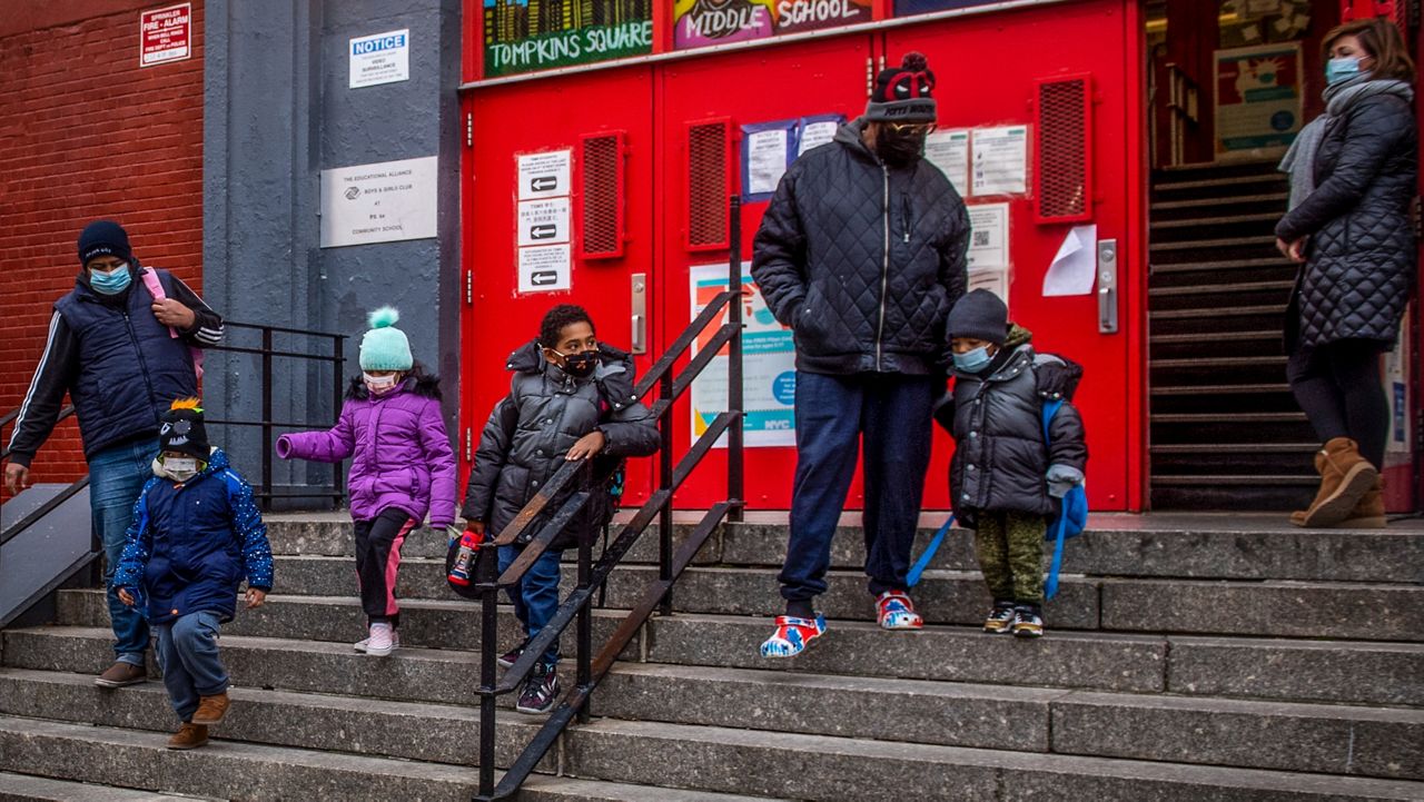 Children and their guardians leave P.S. 64 in the East Village neighborhood of Manhattan on Tuesday, Dec. 21, 2021 in New York.