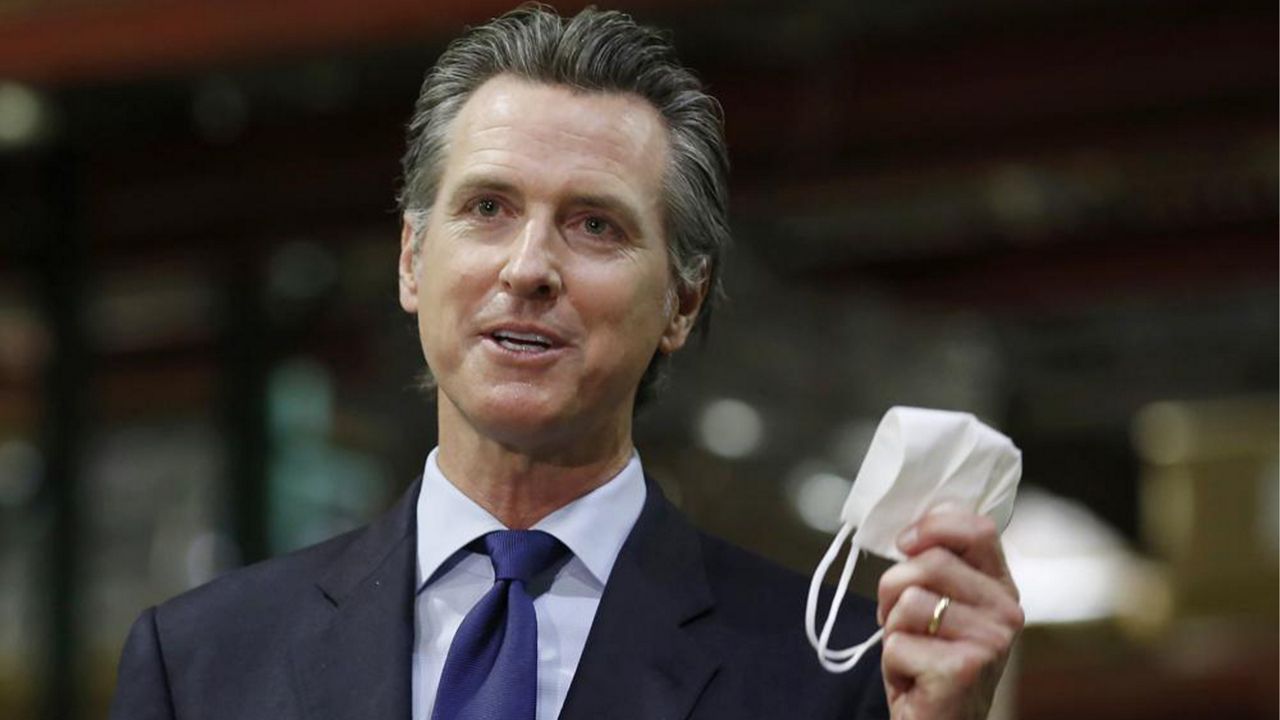 In this June 26, 2020, file photo, California Gov. Gavin Newsom displays a face mask as he calls on people wear them to fight the coronavirus, during a news conference in Rancho Cordova, Calif.  (AP Photo/Rich Pedroncelli, Pool, File)