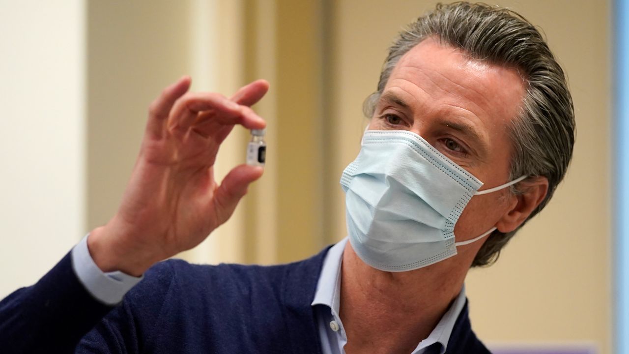 California Gov. Gavin Newsom holds up a vial of the Pfizer-BioNTech COVID-19 vaccine at Kaiser Permanente Los Angeles Medical Center in Los Angeles, Monday, Dec. 14, 2020. (AP Photo/Jae C. Hong)