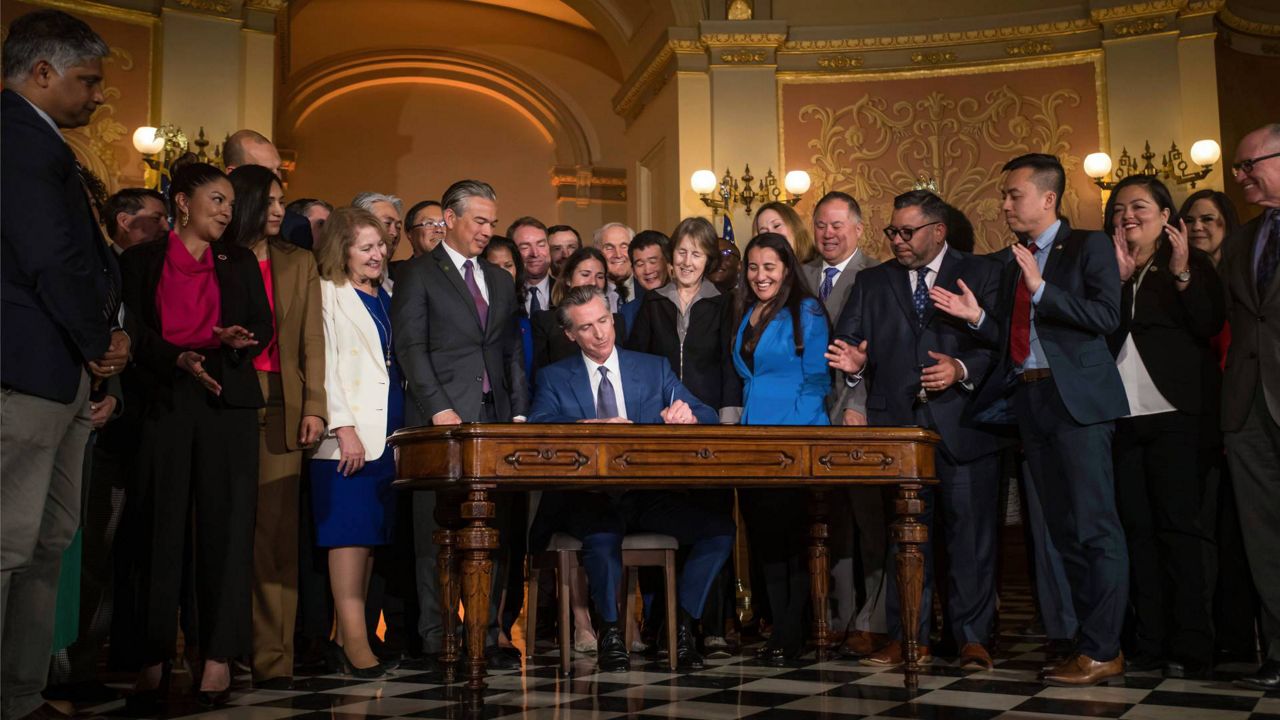 Gov. Gavin Newsom signs a bill aimed at addressing gas price gouging while surrounded by legislators and state officials in the Capitol rotunda Tuesday in Sacramento, Calif. (Xavier Mascareñas/The Sacramento Bee via AP)