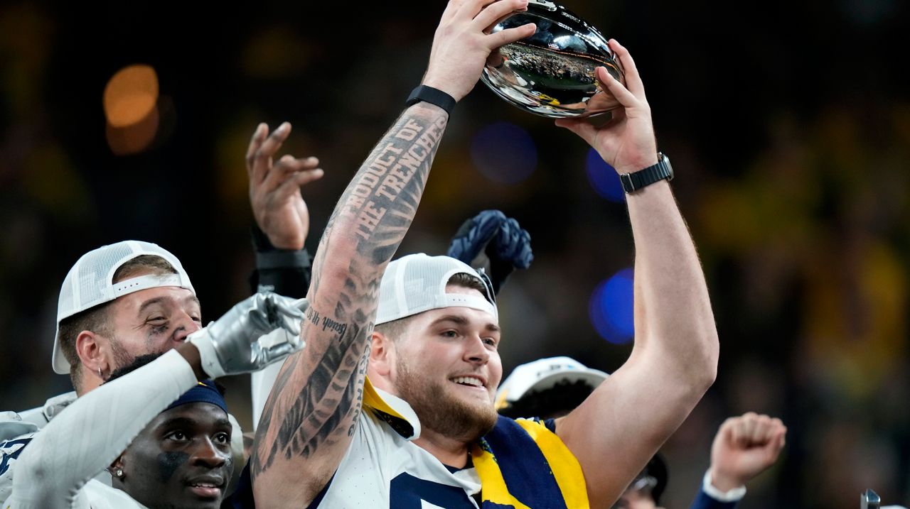 Michigan offensive lineman Zak Zinter (65) holds the trophy after the Big Ten championship NCAA college football game against Iowa, Saturday, Dec. 2, 2023, in Indianapolis. (AP Photo/AJ Mast, File)