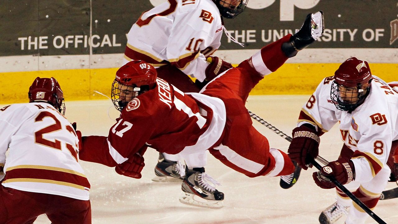 Wisconsin left wing Nic Kerdiles, center, is sent flying after being hit by Denver defenseman Nolan Zajac, right, as center Nick Shore, left, picks up the loose puck in the second period of an NCAA college hockey game in Denver on Friday, Nov. 30, 2012. (AP Photo/David Zalubowski)