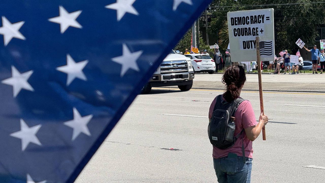 A person stands with a sign demonstrating on what organizers are calling 