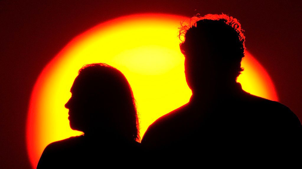 A couple watches the sun set from a park, July 10, 2021, in Kansas City, Mo. (AP Photo/Charlie Riedel)