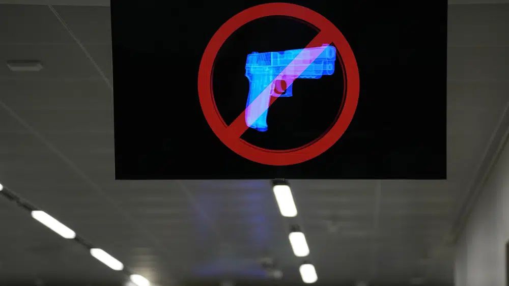 A television displays a "no guns" sign at the Transportation Security Administration security area at the Hartsfield-Jackson Atlanta International Airport on Wednesday, Jan. 25, 2023, in Atlanta. Last year saw a record number of guns intercepted at airport checkpoints across the country. The numbers have been steadily climbing and hit 6,542 last year. The head of the Transportation Safety Administration, David Pekoske, says this is a reflection of what is going on in society and in “society there are more people carrying firearms.” (AP Photo/Brynn Anderson)