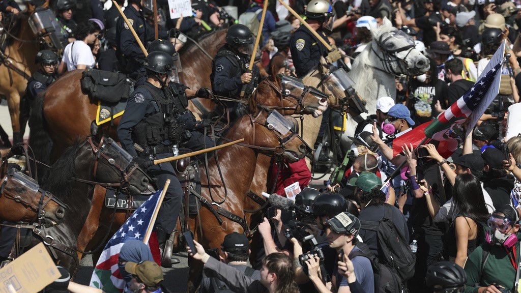 Demonstrators standoff against law enforcement on horseback during a protest Saturday, June 14, 2025, in Los Angeles. (AP Photo/Ethan Swope)