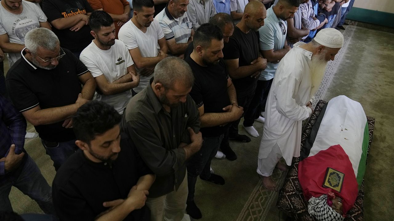 Palestinian mourners pray at the body of Mohammad Hoshiya, 12, during his funeral in the West Bank village of Qatana, southwest of Ramallah