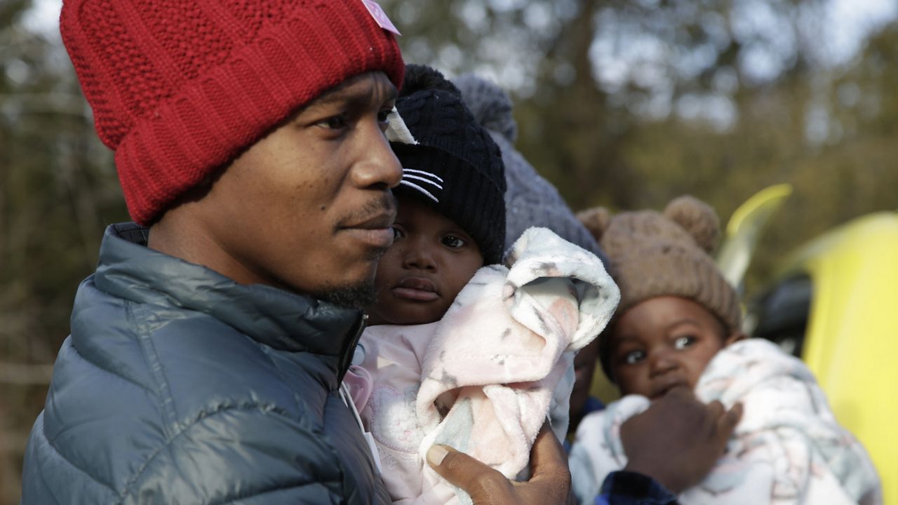 Haitian migrant Gerson Solay, 28, carries his daughter, Bianca, as he and his family cross into Canada Friday at the non-official Roxham Road border crossing north of Champlain, N.Y. (AP Photo/Hasan Jamali)