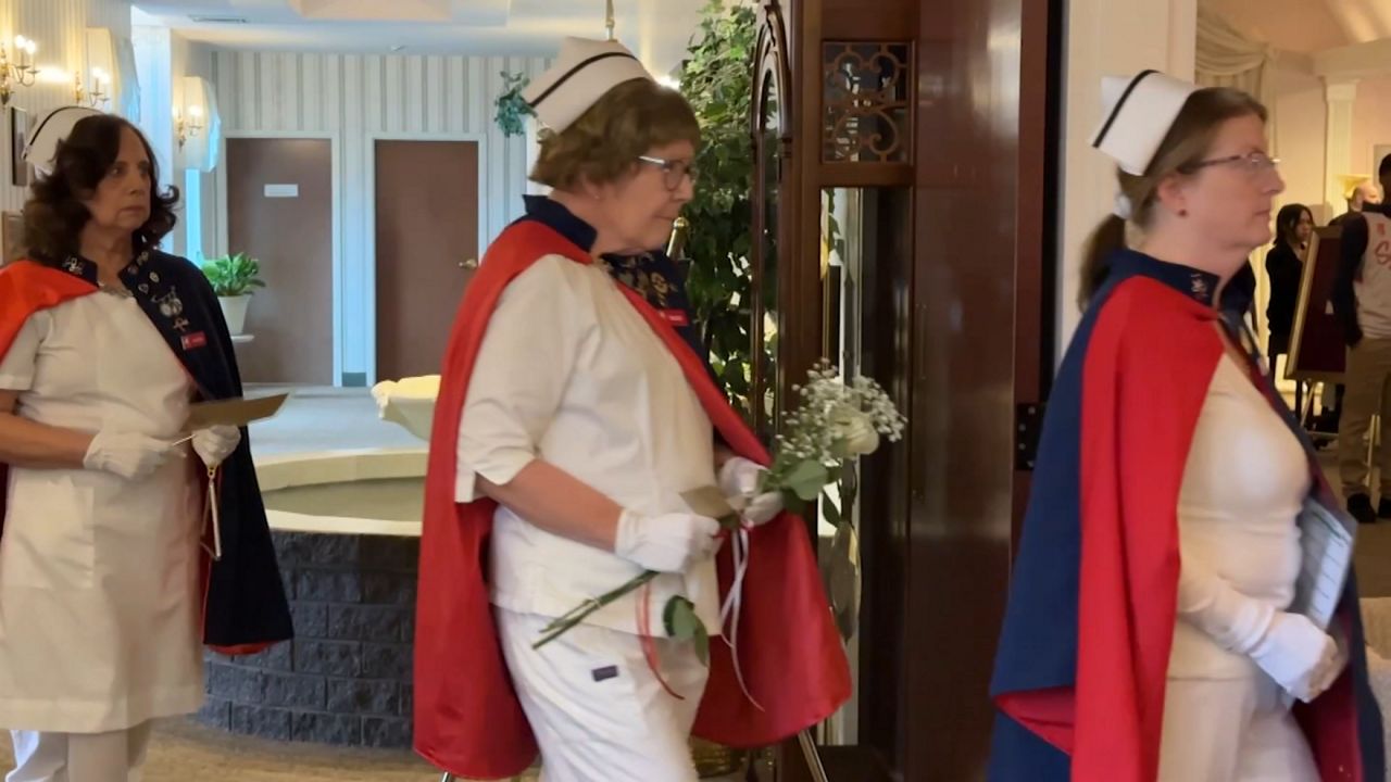 nurses honor guard, in uniform, walk into a funeral service