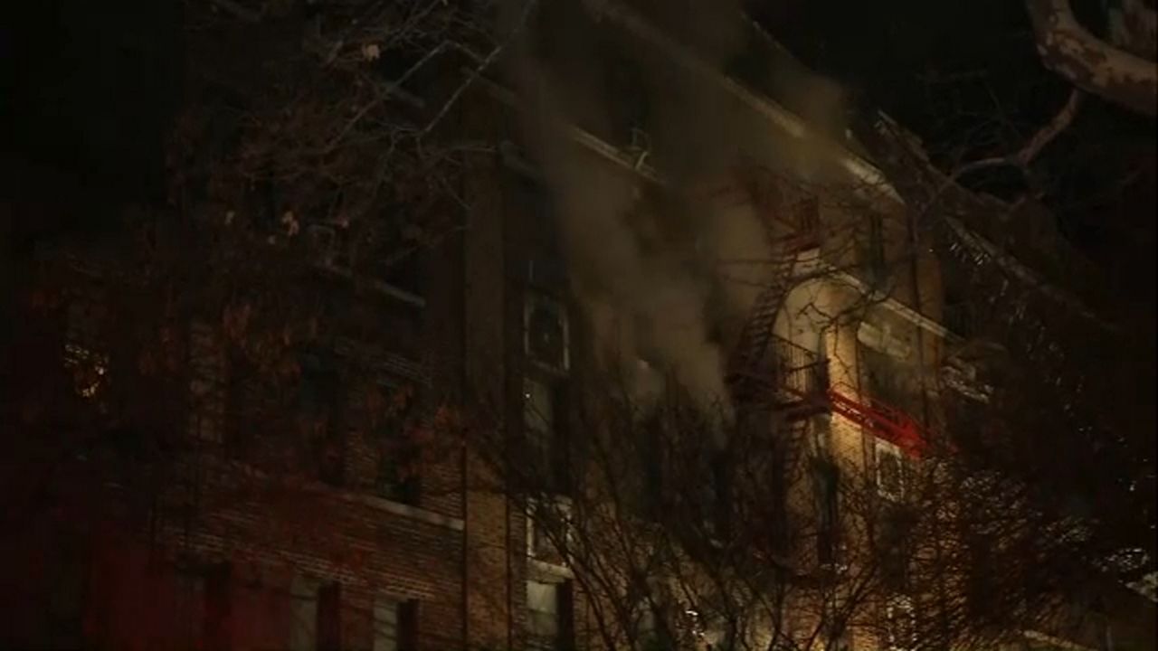 Dark smoke billows near a fire escape attached to a building.