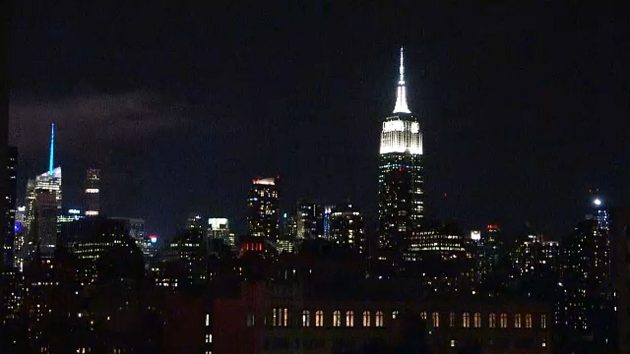 The Empire State Building and dozens of smaller other skyscrapers lit up against a skyline.