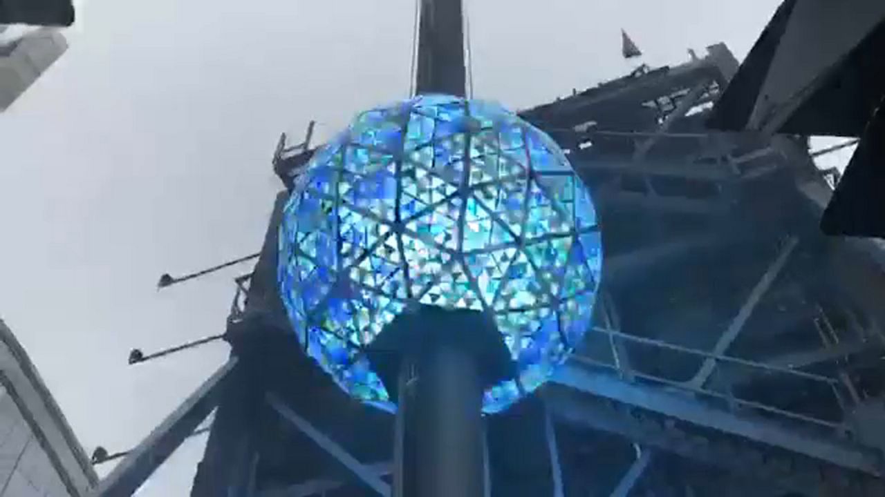 A sphere on a pole, shining blue on the inside. A cloudy sky is seen above it.
