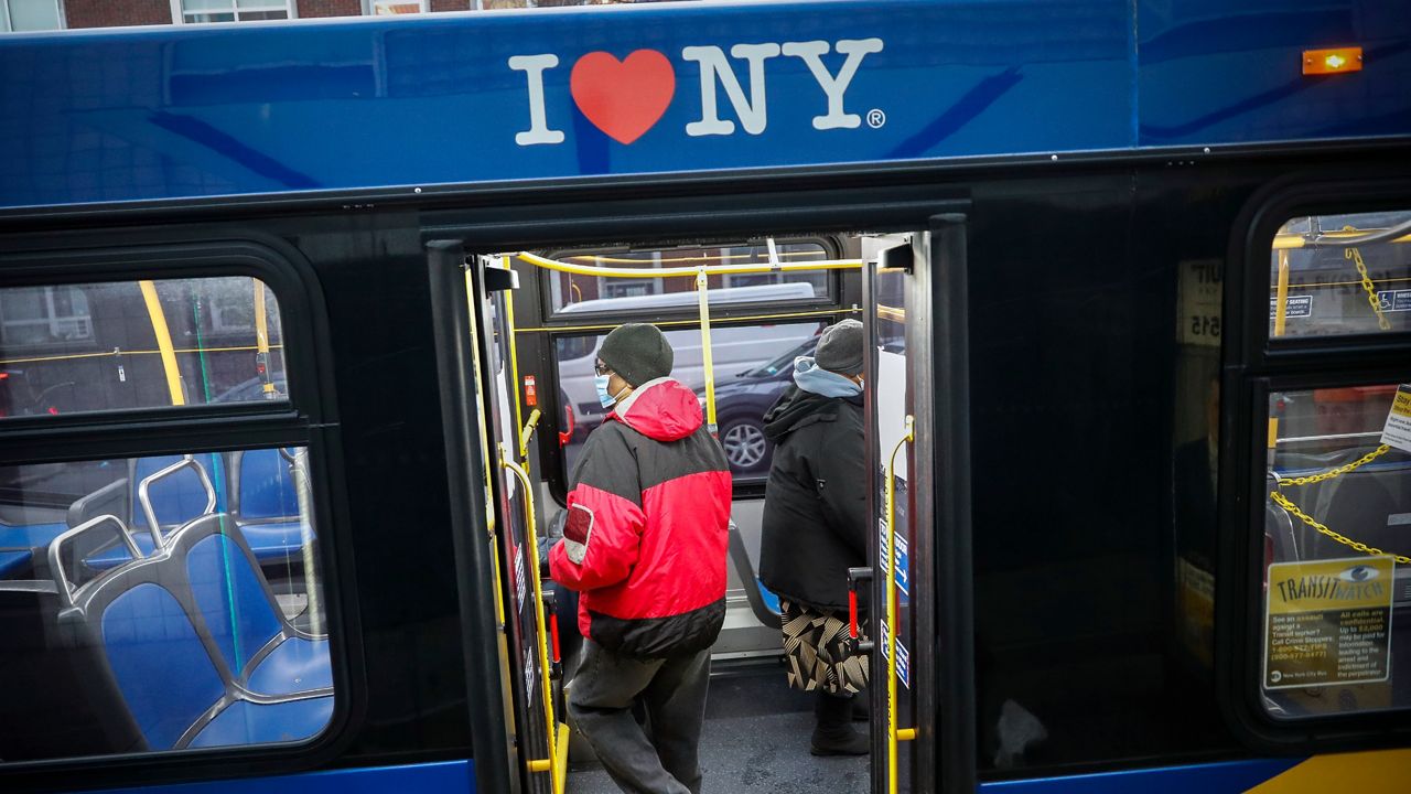 A man in a red coat boards the back of an MTA bus in New York. 