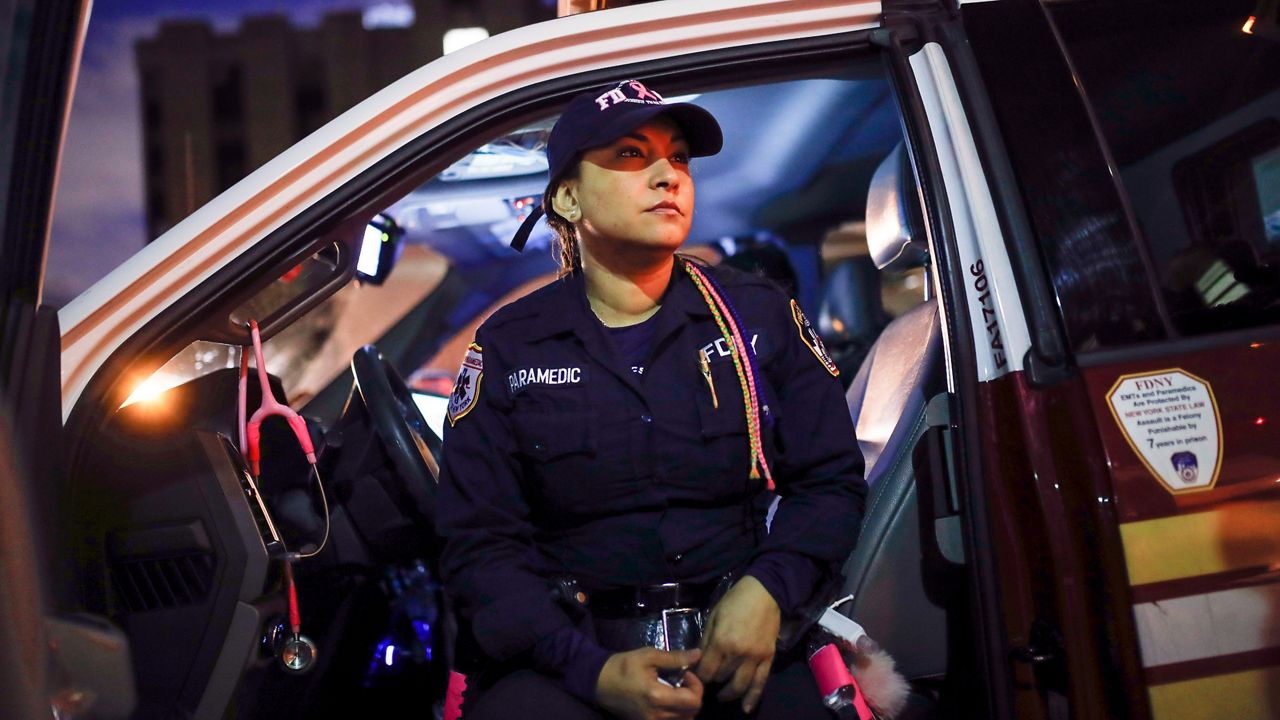 FDNY paramedic Elizabeth Bonilla wears her multicolored braids as she sits in her ambulance between calls after delivering a patient to Jacobi Medical Center, April 15, 2020, in the Bronx borough of New York. Four New York City ambulance workers, including Bonilla, who said they were disciplined for speaking to the media during the first harrowing months of the COVID-19 pandemic, have reached a settlement in their free speech lawsuit against the fire department and the city, their union announced Wednesday, March 1, 2023. (AP Photo/John Minchillo)