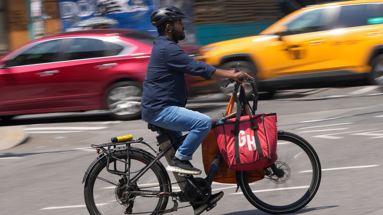 A delivery worker rides a motorized bicycle in New York on Tuesday, July 25, 2023.