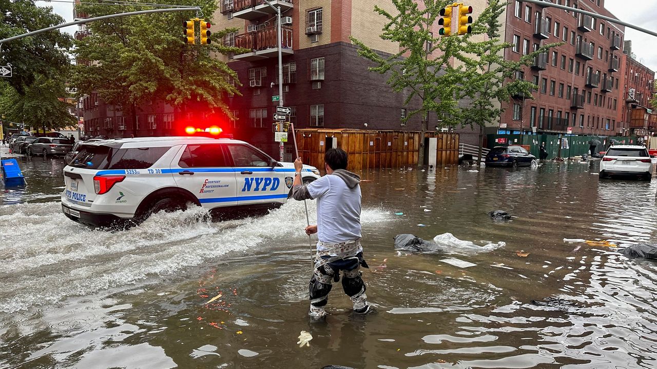 A man works to clear a drain in flood waters on Friday, Sept. 29, 2023 in Brooklyn.