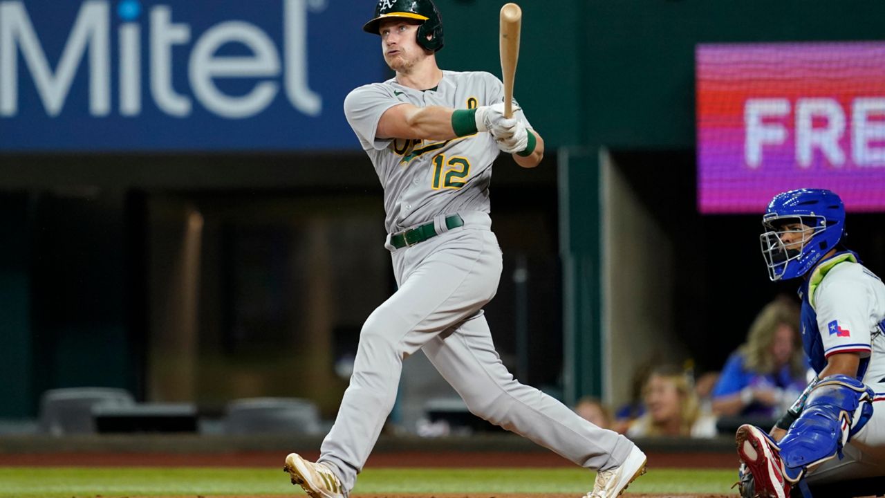 Oakland Athletics' Sean Murphy (12) follows through on a solo home run swing as Texas Rangers catcher Meibrys Viloria looks on in the first inning of a baseball game, Wednesday, Aug. 17, 2022, in Arlington, Texas. (AP Photo/Tony Gutierrez)