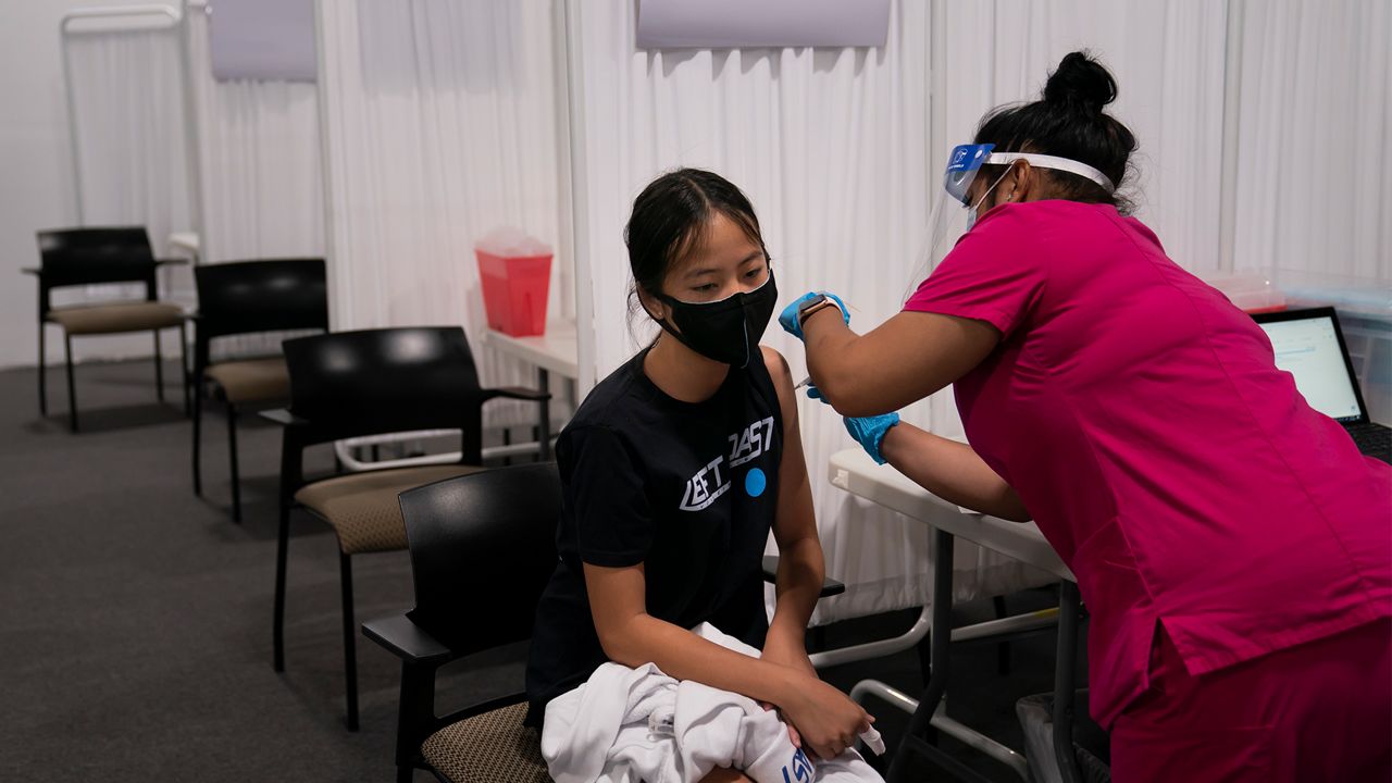 Melody Chuang, 14, receives her first dose of the Pfizer COVID-19 vaccine from medical assistant Gloria Urgell at Providence Edwards Lifesciences vaccination site in Santa Ana, Calif., May 13, 2021. (AP Photo/Jae C. Hong)