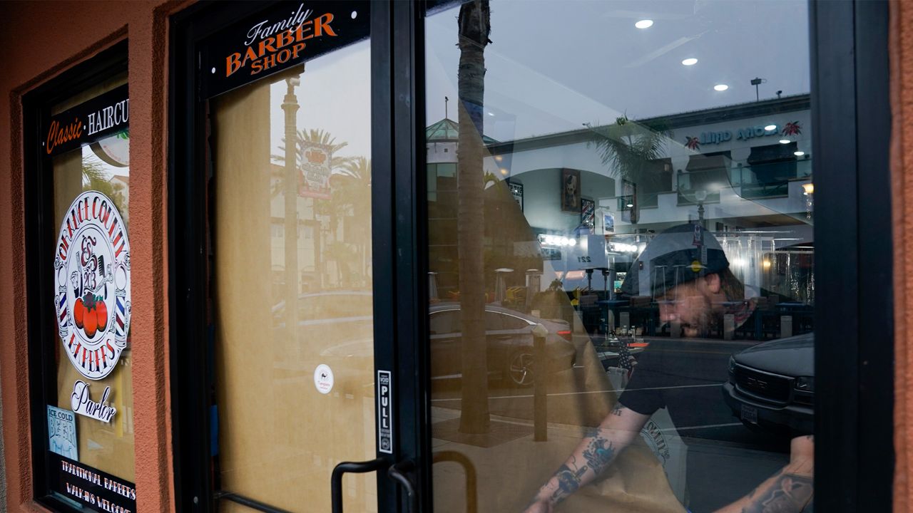 Saul Arvizu, a barber at Orange County Barbers Parlor, opens the shop, Wednesday, May 27, 2020, in Huntington Beach, Calif.  (AP Photo/Ashley Landis)