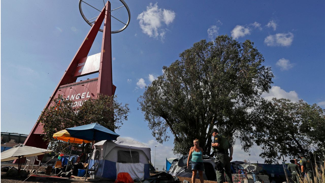 In this Sept. 22, 2017 photo, deputies with the Orange County Sheriff's Department make routine contact with people camped outside Angel Stadium in Anaheim, Calif. (AP Photo/Chris Carlson)