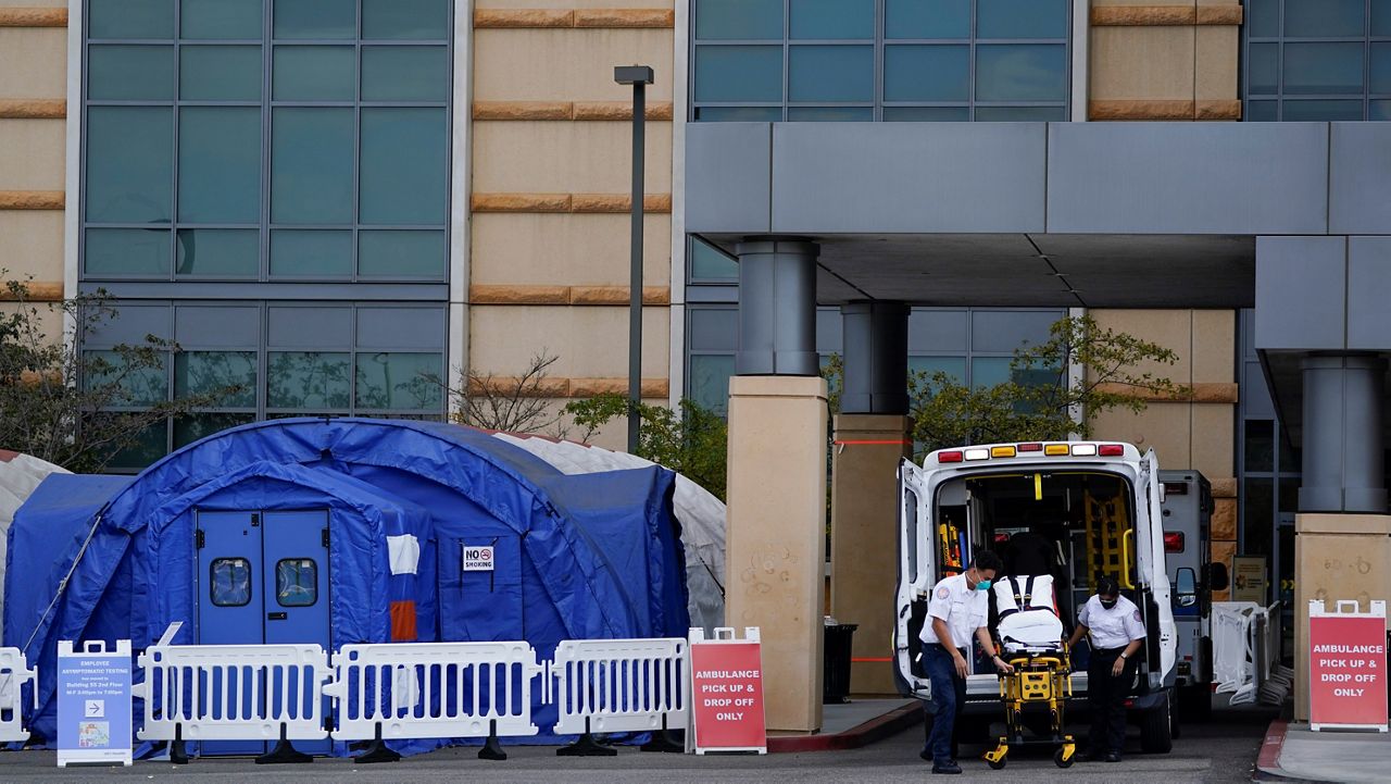 In this Dec. 17, 2020, file photo, medical workers remove a stretcher from an ambulance near medical tents outside the emergency room at UCI Medical Center, in Irvine, Calif. (AP Photo/Ashley Landis)