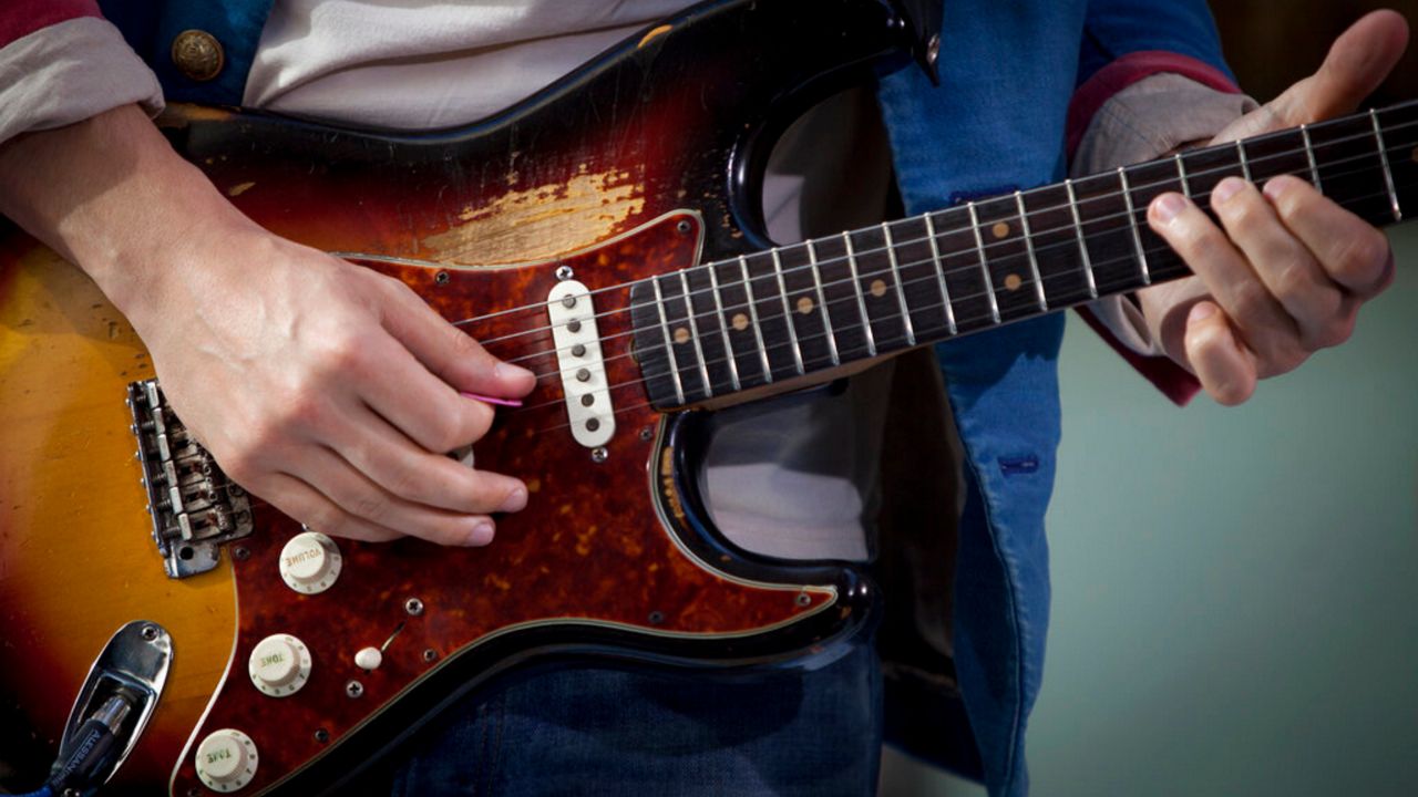 person strumming electric guitar, zoomed in on hands and guitar